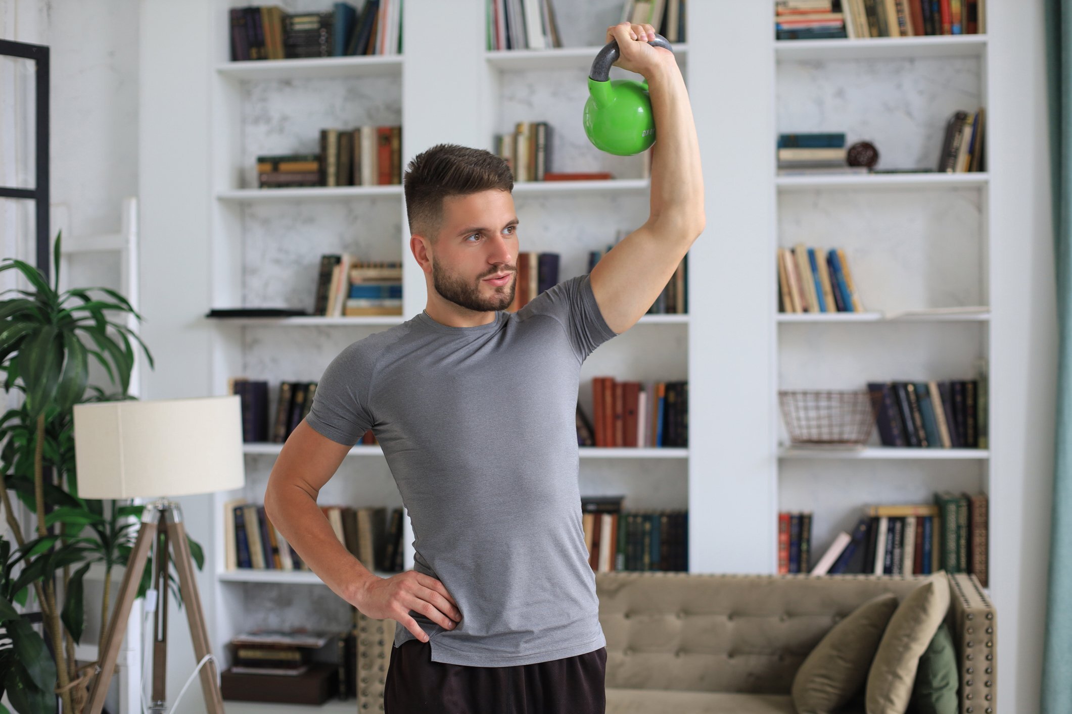 Handsome man doing sport exercise with kettlebell at home. Concept of healthy life.